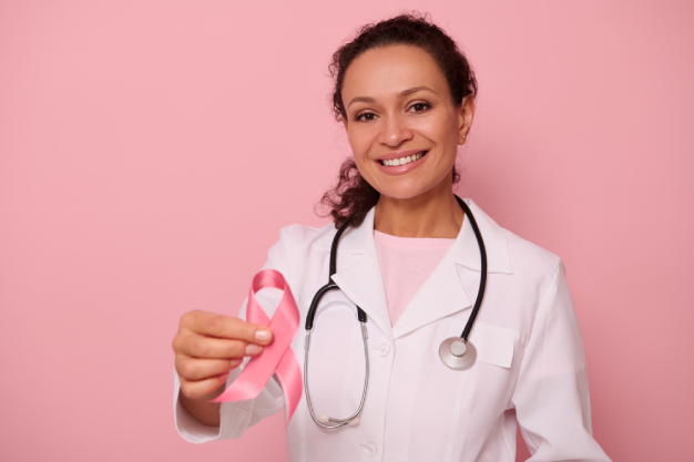 gorgeous-african-american-female-doctor-with-beautiful-toothy-smile-showing-pink-satin-ribbon-isolated-colored-background-with-copy-space-world-day-fight-breast-cancer-1-st-october-concept